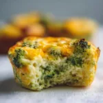 bitten broccoli cheddar egg muffin on white cloth