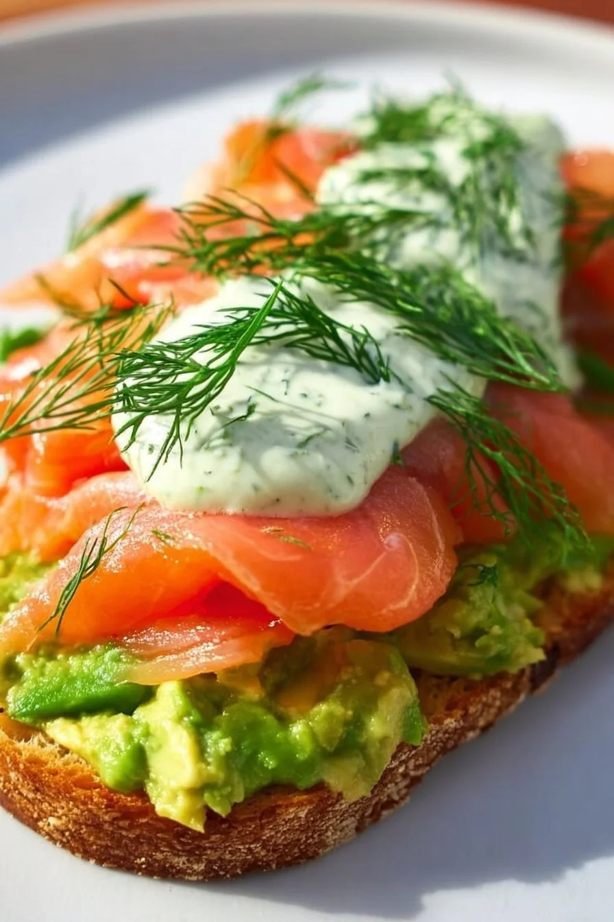 Avocado Toast topped with Smoked Salmon, garnished with herbs.
