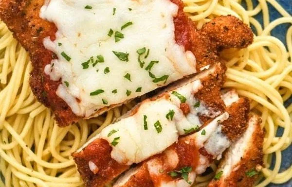 Delicious Chicken Parmesan served with pasta and fresh herbs