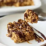 Baked oats in a glass dish garnished with fresh fruits and nuts