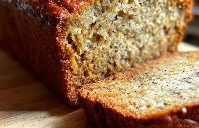 High-Protein Banana Bread banana bread Slice of high-protein banana bread on a wooden cutting board