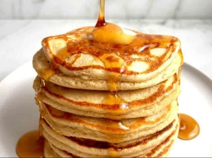 Stack of high-protein pancakes topped with berries and syrup